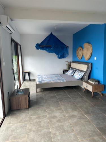 1 dormitorio con cama y pared azul en la maison du nord en Acoua