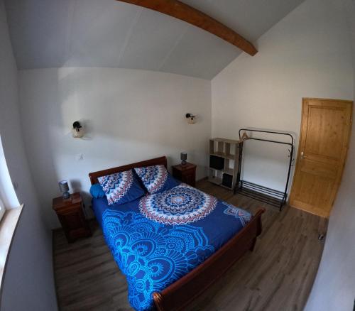 a bedroom with a bed with a blue comforter at Gîte des quatre saisons in Thilay