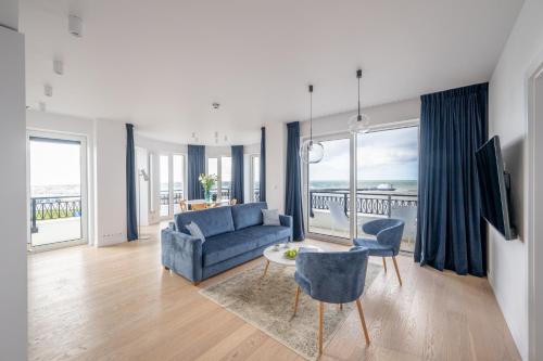 uma sala de estar com um sofá azul e uma mesa e cadeiras em Marina Royale Darłowo - Apartamenty Vista Mar nad morzem em Darłowo