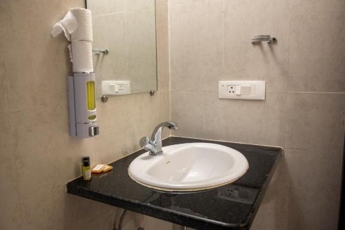 a white sink in a bathroom with a mirror at Ronnie's Studio Apartment in Arpora