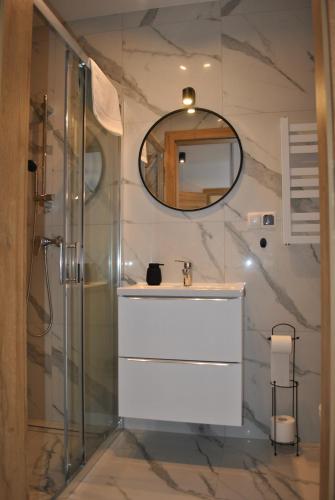 ein Bad mit einem Waschbecken und einem Spiegel in der Unterkunft Apart4You Apartamenty Nowy Targ in Nowy Targ