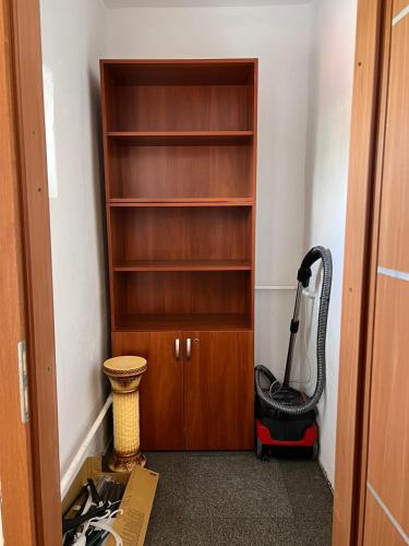 a room with a vacuum cleaner next to a book shelf at Csokonai Apartman in Salgótarján