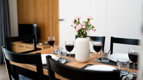 a table with glasses of wine and a vase with flowers at Apartamenty Good Time - Stone Hill IV in Szklarska Poręba