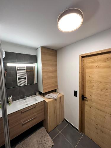 La salle de bains est pourvue d'un lavabo et d'une porte en bois. dans l'établissement Très bel appartement au gets, aux Gets