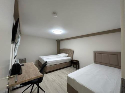 een kamer met 2 bedden, een bureau en een televisie bij Rheinischer Hof Appartements in Leverkusen