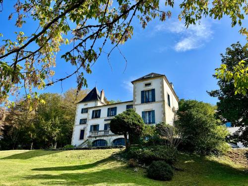 duży biały budynek na wzgórzu z drzewami w obiekcie Richard Lequet Domaine gastronomique du Val d Atur w mieście Boulazac