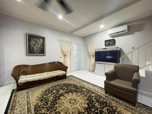 a living room with a couch and a chair and a television at Venice Raudhah Guest House in Lumut