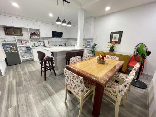 a kitchen and dining room with a wooden table and chairs at Venice Raudhah Guest House in Lumut