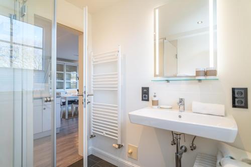 a white bathroom with a sink and a shower at Appartement Meeresleuchten - Nicolinenhof in Wenningstedt