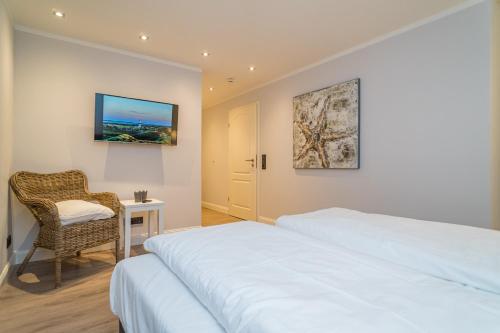 a bedroom with a bed and a chair and a desk at Appartement Lachmöwe - Nicolinenhof in Wenningstedt