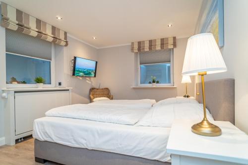two beds in a room with two windows at Appartement Meeresleuchten - Nicolinenhof in Wenningstedt