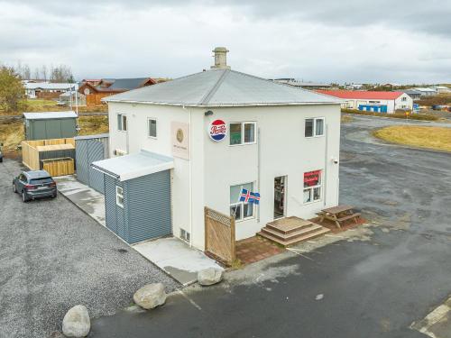 a large white building in a parking lot at MB Guesthouse in Grímsnes og Grafningshreppur