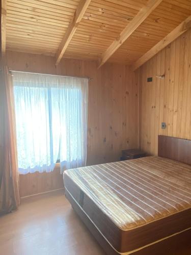 - une chambre avec un lit dans une pièce dotée d'une fenêtre dans l'établissement Cabañas menetue, à Curarrehue