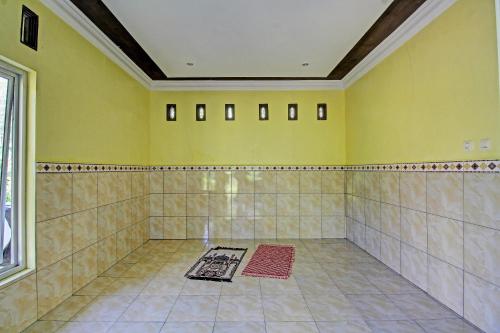 baño grande con paredes amarillas y suelo de baldosa. en OYO 91177 Desa Wisata Duren Sari, en Tasikmadu