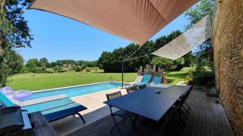 d'une terrasse avec une table bleue et des chaises à côté de la piscine. dans l'établissement Le Clos d'Ô Les Rapiettes maison proche Sarlat avec piscine privée, à Prats-de-Carlux