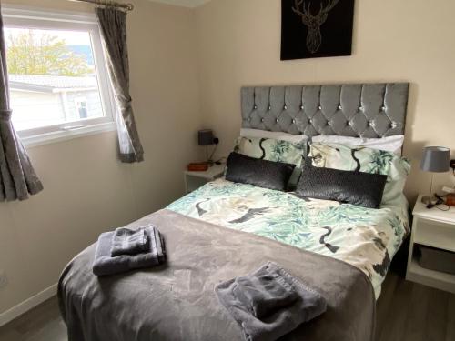 a bedroom with a large bed with a large window at Lovely new caravan by Loch Long in Cove