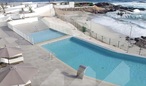 a large swimming pool next to a beach with umbrellas at Lindo departamento al borde de la playa in Iquique