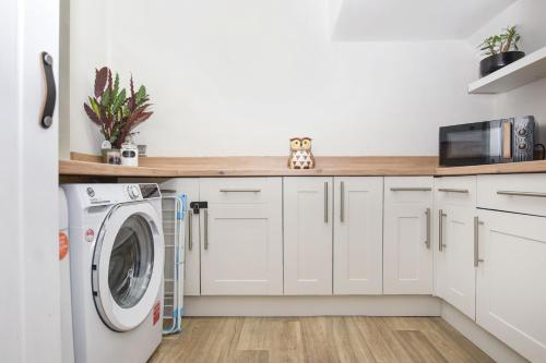 a kitchen with white cabinets and a washer and dryer at Panoramic Sunset Views - Free Parking & Sleeps 5 in Heywood