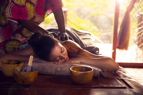 Una donna sdraiata su un tavolo a farsi fare un massaggio di Fruit & Spice Wellness Resort Zanzibar a Kizimkazi
