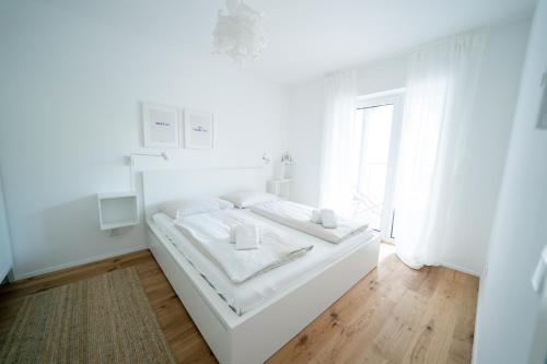 ein weißes Schlafzimmer mit einem weißen Bett und einem Fenster in der Unterkunft Apartment Seekind by Cosy Homes in Reifnitz