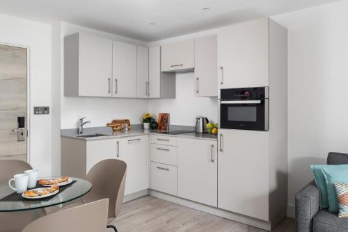 a kitchen with white cabinets and a table at Q Square by Supercity Aparthotels in Brighton & Hove