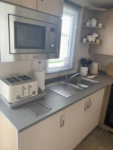 a kitchen with a sink and a microwave at Bude 13 in Cubert