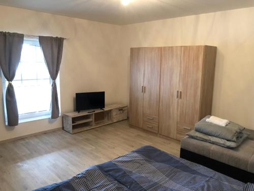 um quarto com uma cama, uma televisão e um armário em Ferienhaus Staßfurt em Stassfurt