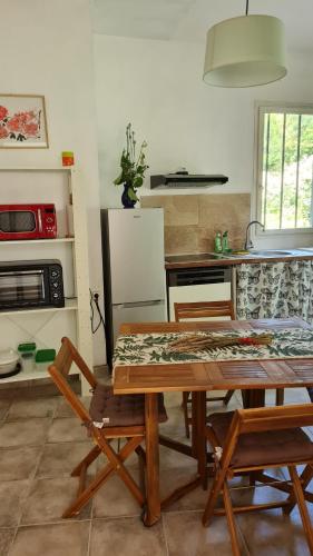 a kitchen with a wooden table with chairs and a refrigerator at gîte du bambou bleu 