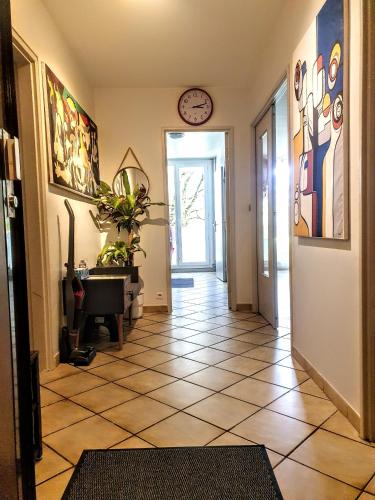 a hallway with a tile floor and a clock on the wall at La Casa Picasso in Villepinte
