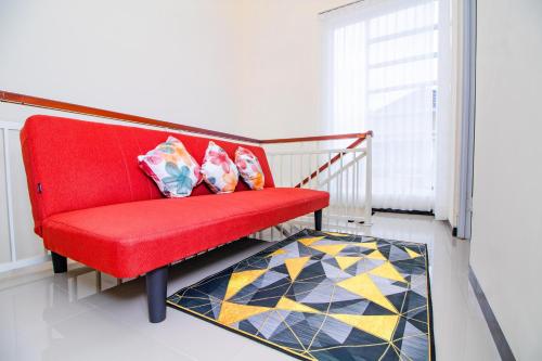 巴图Villa Mulyo E4 by Sans Villa的地毯上带两个枕头的红色椅子