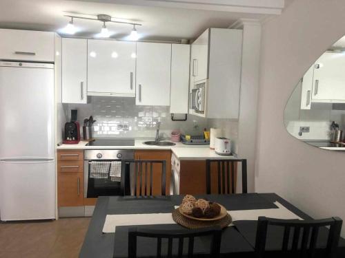 een keuken met witte kasten en een tafel met stoelen bij Apartamento en Santoña in Santoña