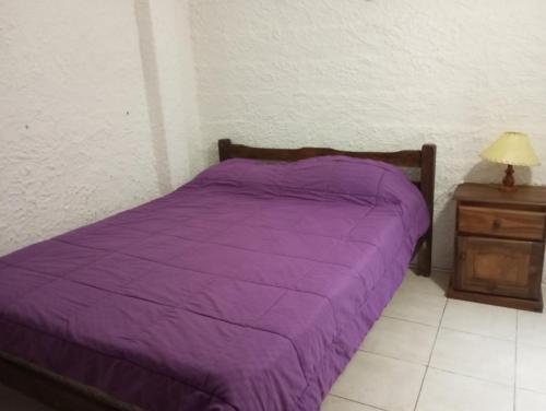 uma cama roxa num quarto com mesa de cabeceira em Gloria em Piriápolis