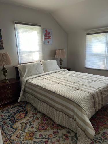 a large bed in a bedroom with two windows at A Spicy Swedish Cottage in Salt Lake City