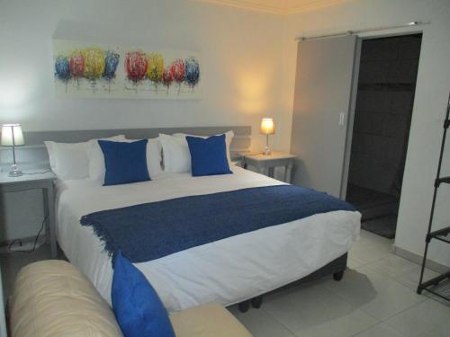 1 dormitorio con 1 cama grande con almohadas azules y blancas en LEKKER RUS, en Bloemfontein