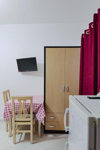 a kitchen with a table and a cabinet with a tv on it at Vila Shpetimi in Ksamil