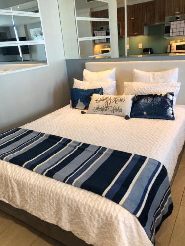 Elle comprend un grand lit avec des oreillers bleus et blancs. dans l'établissement Stunning sea facing apartment, à Durban
