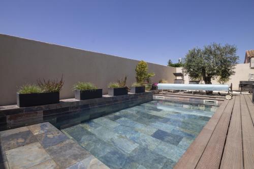 une piscine avec des plantes en pot et une terrasse en bois dans l'établissement Maison des Fleurs, à Vedène