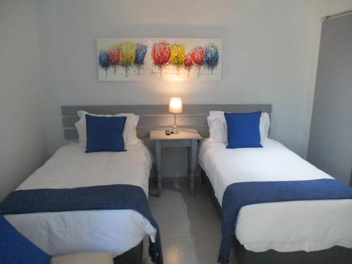 2 camas en una habitación con una mesa y una lámpara en LEKKER RUS, en Bloemfontein