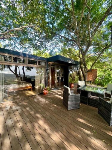 a deck with chairs and a table and a tree at Sweet Jungle Beach in Bejuco