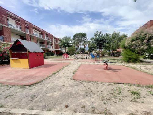 einen Spielplatz mit einem Hundehaus vor einem Gebäude in der Unterkunft 2950-Appartement 4 pers avec piscine in Argelès-sur-Mer
