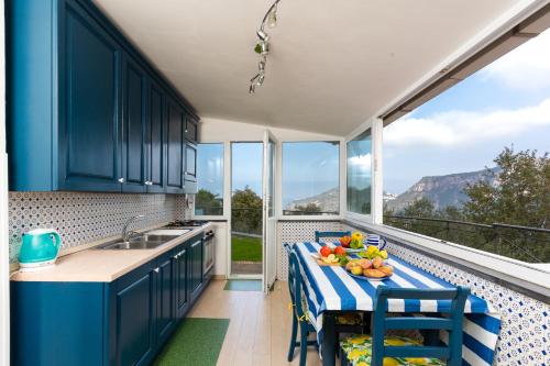 ピアノ・ディ・ソレントにあるVilla Fanella, between Sorrento & Amalfiのキッチン(青いキャビネット、フルーツ付きのテーブル付)