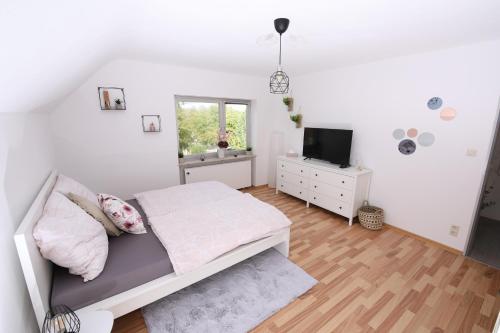 a white bedroom with a bed and a tv at NATURBLICK Apartments: Moderne Ferienwohnung in Grebenhain