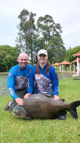 a man and a woman sitting on top of a large fish at Pousada & Pesca Esportiva Fazolin in Socorro