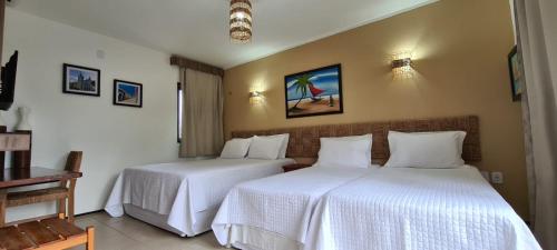2 bedden in een hotelkamer met witte lakens bij Pousada Coqueiro Beach in Luis Correia