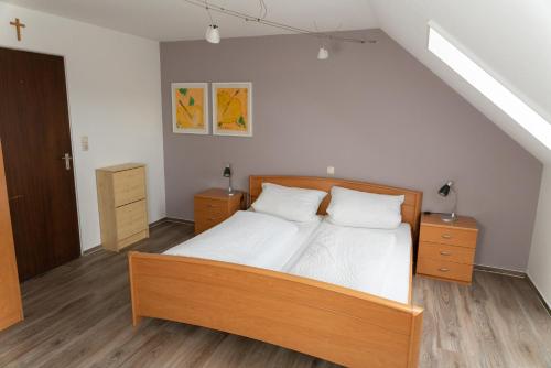 1 dormitorio con 1 cama con sábanas blancas y suelo de madera en Gasthaus Schneider, en Bad Bocklet