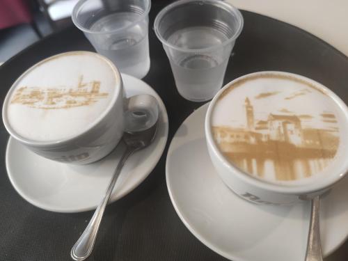 a cup of coffee on a table with glasses of water at Maison Divino in Trani