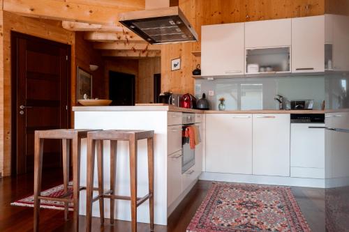 a kitchen with white cabinets and a table and stools at Strohlehm'zhaus in Weiden am See
