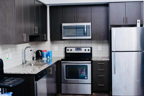 cocina con armarios negros y nevera blanca en Fully Equipped 1BR Condo Vaughan - Toronto en Vaughan