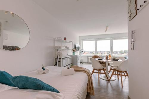 Schlafzimmer mit einem Bett, einem Tisch und Stühlen in der Unterkunft Moderne lichtrijke studio vlakbij strand en casino Middelkerke in Middelkerke