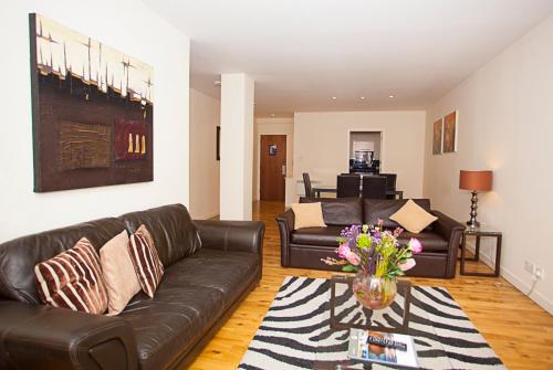 a living room with a leather couch and a table at Trinity Quay Apartments in Aberdeen